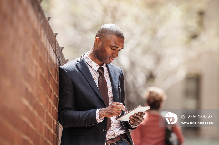 Young man using digital tablet near wall