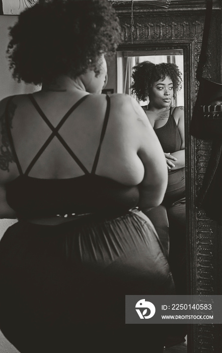 Black woman looking in mirror admiring herself