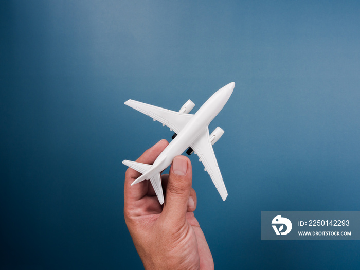 蓝色背景下的手持白色飞机玩具模型，俯视图，简约风格。白色飞机，fl