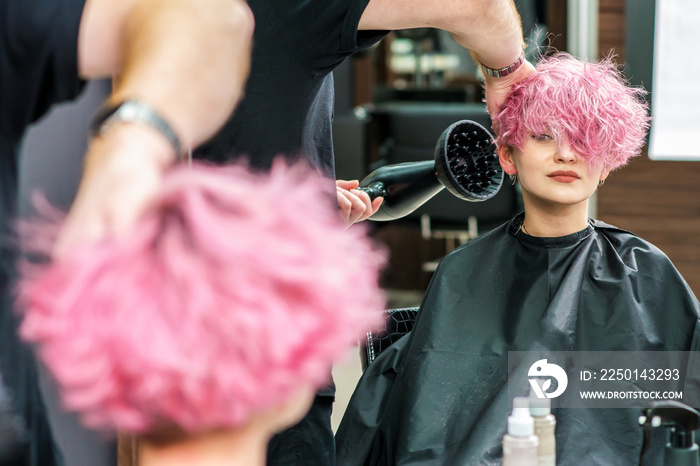 Hairdresser dries hair with a hairdryer