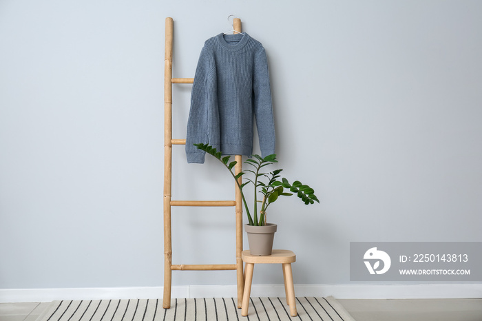 Sweater hanging on ladder near color wall in room