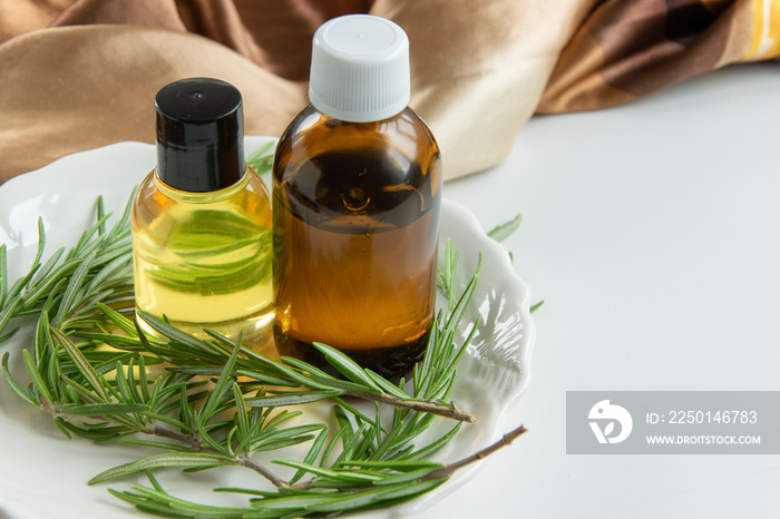 Bottles with rosemary essential oil. Herbal cosmetic treatment products.