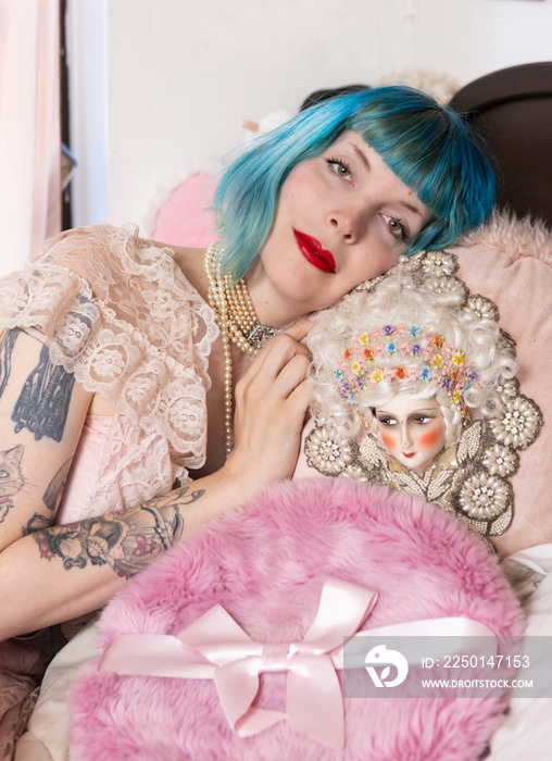 portrait of woman with blue hair with vintage pillows on bed