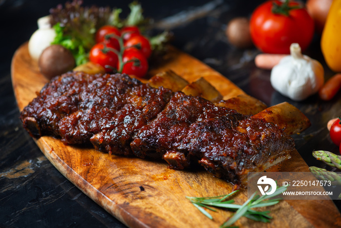 BBQ beef ribs steak served with a hot chili pepper and fresh tomatoes on an old vintage wooden cutti