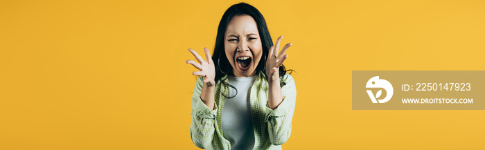 angry asian woman gesturing and yelling isolated on yellow