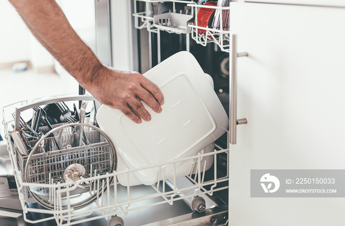 close-up of person emptying or loading dishwasher in kitchen