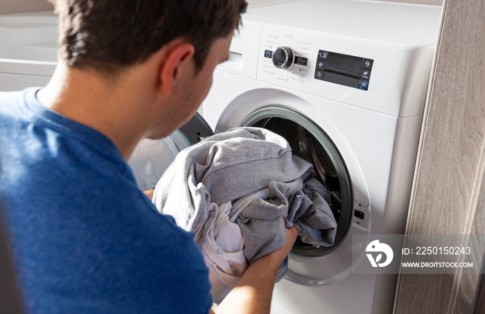 Man loading the washer dryer with clothes