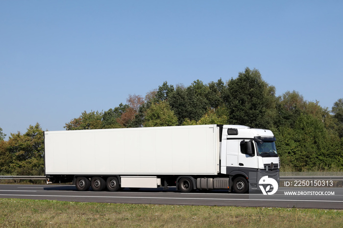 Weißer Truck unterwegs auf gepflegtem Abschnitt einer deutschen Autobahn im Sommer