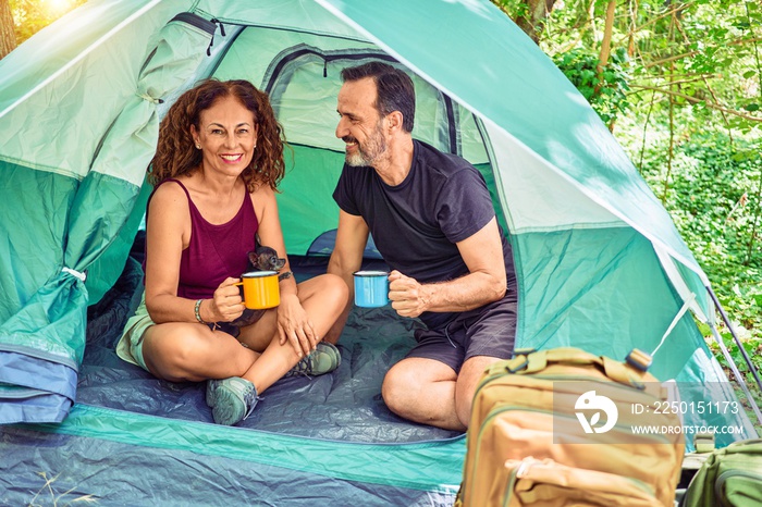 Middle age couple  of hiker smiling happy looking at the camera. Drinking coffee camping at the fore