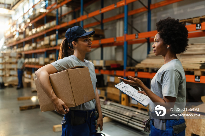 Two female workers communicating in distribution warehouse.