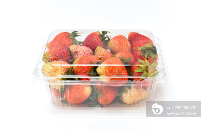 近距离观察塑料透明包装中接近成熟的红色草莓，在白色背景上隔离