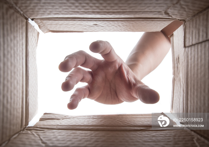 Man is stretching hand into cardboard box,View from the box