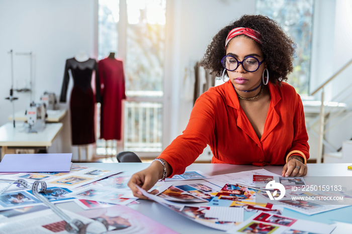 Busy good-looking bronzed girl in bright outfit choosing photos