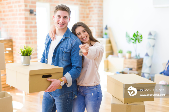 Beautiful young couple hugging in love and showing keys of new house, smiling happy moving to a new 