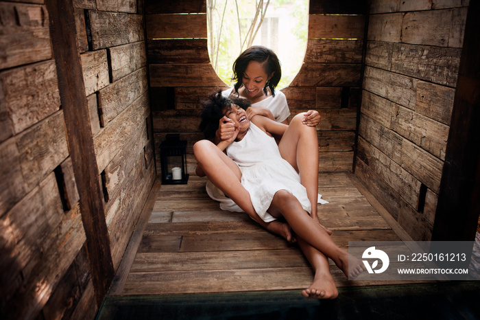 Girl (8-9) laughing with mother in tree house