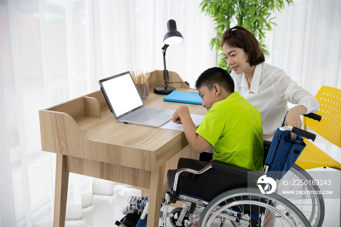 Asian boy with disability in wheelchair drawing picture with Laptop and mother at home. Supportive, 