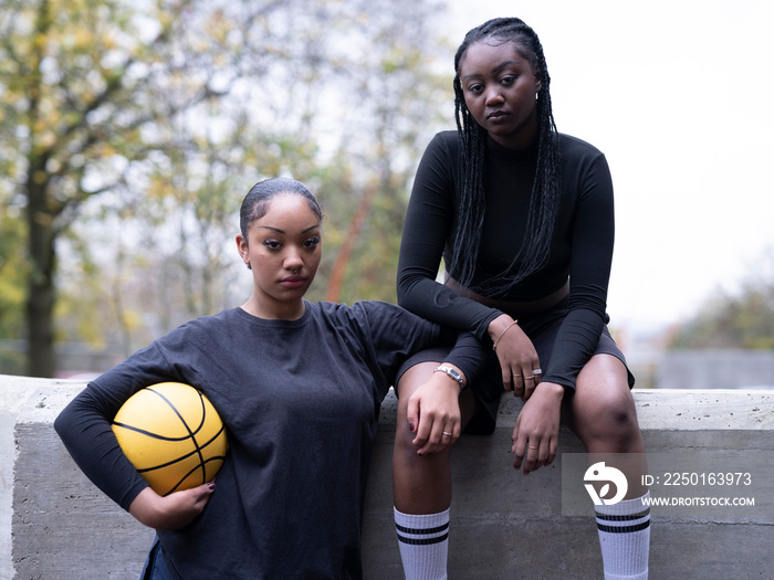 Portrait of female friends outdoors holding basketball ball