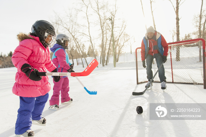 Father and daughters playing ice hockey