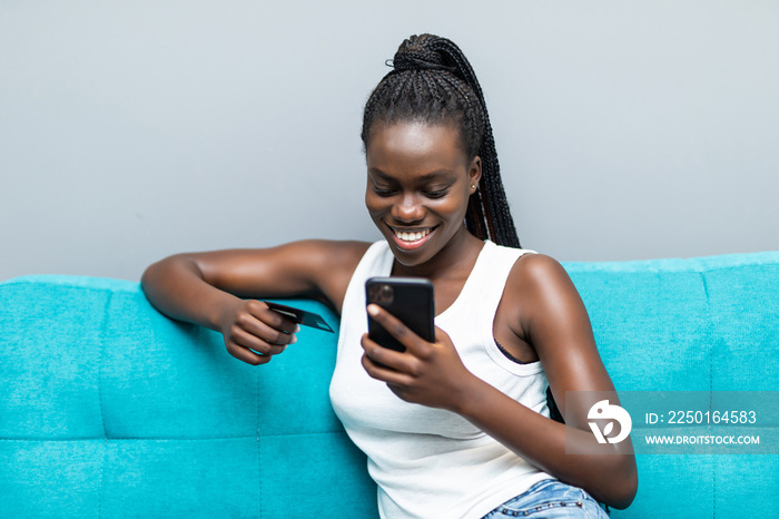 非裔美国妇女坐着手机使用信用卡进行网上购物和银行业务