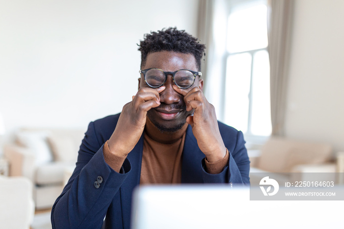 Tired African American businessman taking off glasses, exhausted employee massaging nose bridge, suf