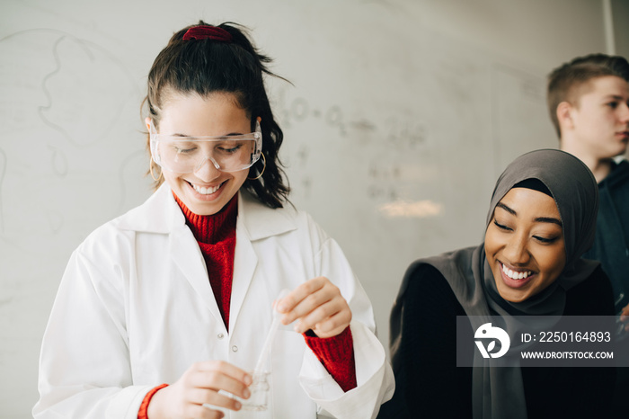 Smiling female friends studying chemistry in high school