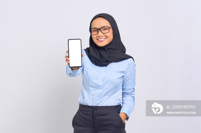 Portrait of smiling young Asian woman showing blank screen mobile phone isolated on white background