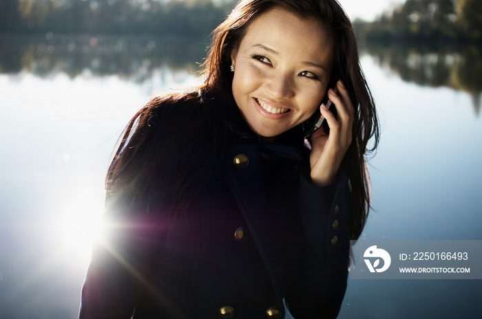 Woman talking on cell phone by lake