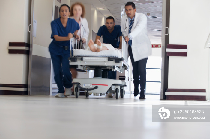 Doctors and nurses rushing patient on stretcher in hospital corridor