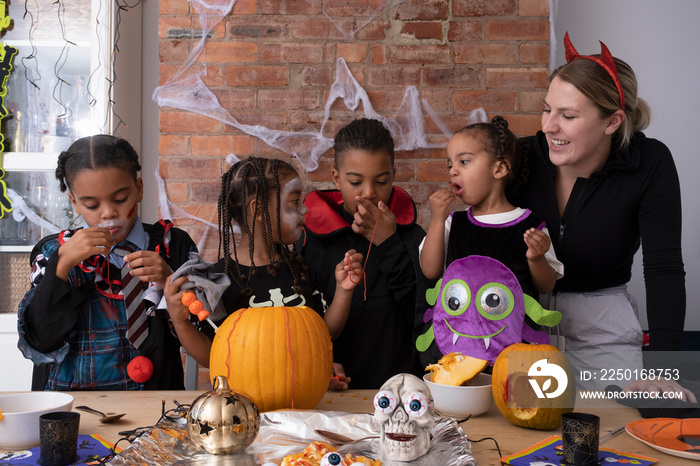 Family in Halloween costumes making Jack�OLantern