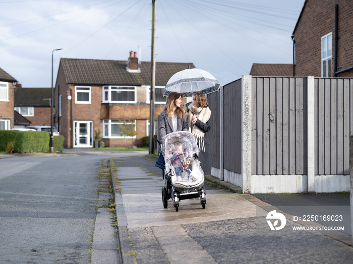 Lesbian couple walking with baby in stroller�