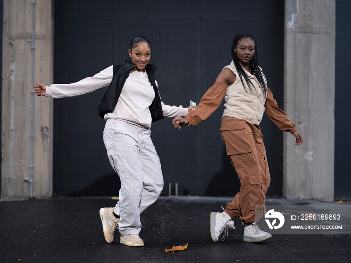 Two teenage girls dancing in city