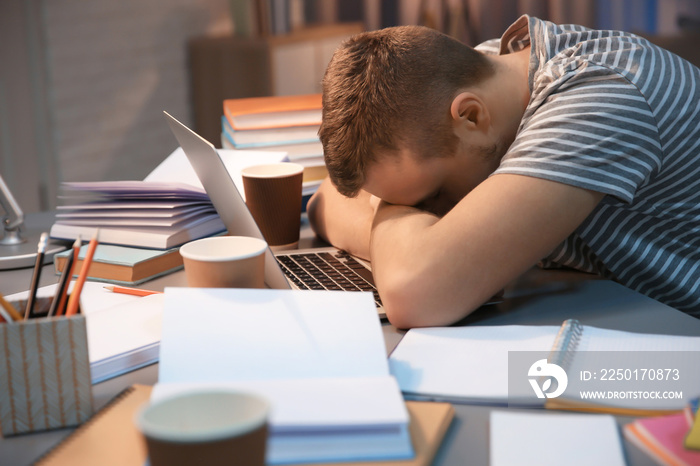 Tired student sleeping at table indoors