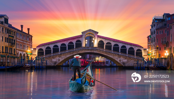 Gondolier carries tourists on gondola near Rialto Bridge - Venice, Italy