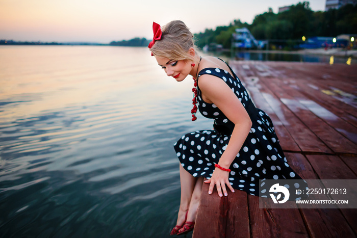 A beautiful young woman dressed sitting on the pier