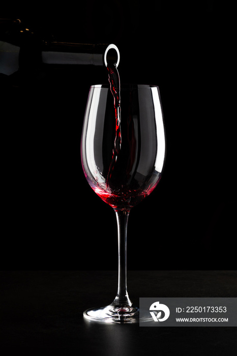 红酒倒进杯子里，溅到杯子侧面。低调的黑色背景。