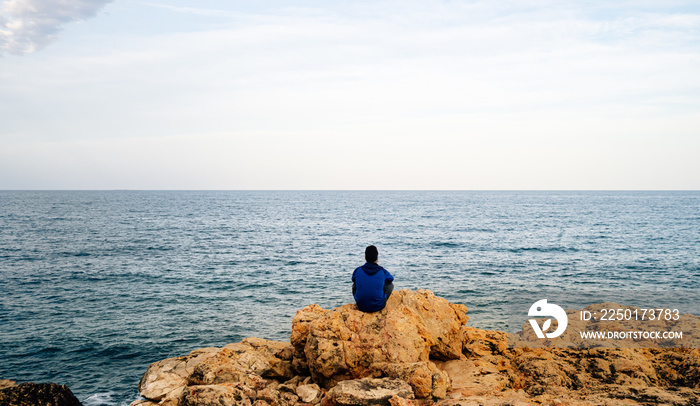 沉思的人坐在面朝大海的悬崖上。反省自我认识的概念