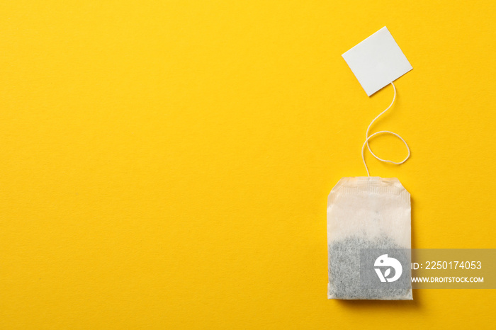 Tea bag with label on yellow background, space for text