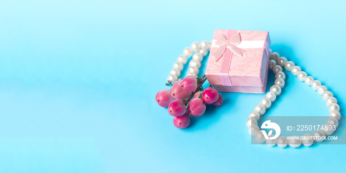 gift box pearl necklace and a bouquet of flowers on a blue background banner, partial blur, March 8,