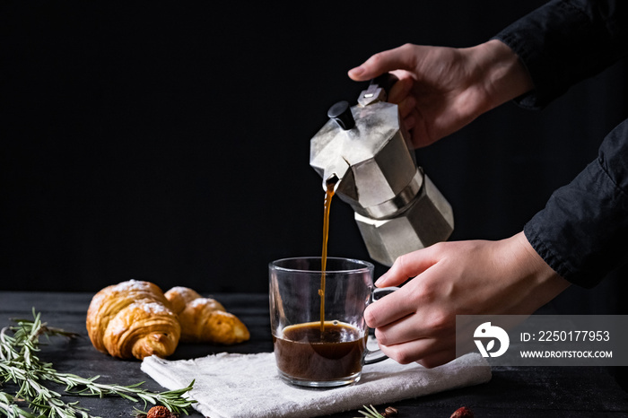 Pouring coffee from an italian percolator, shot in low key. Male hands pour black coffee from italia