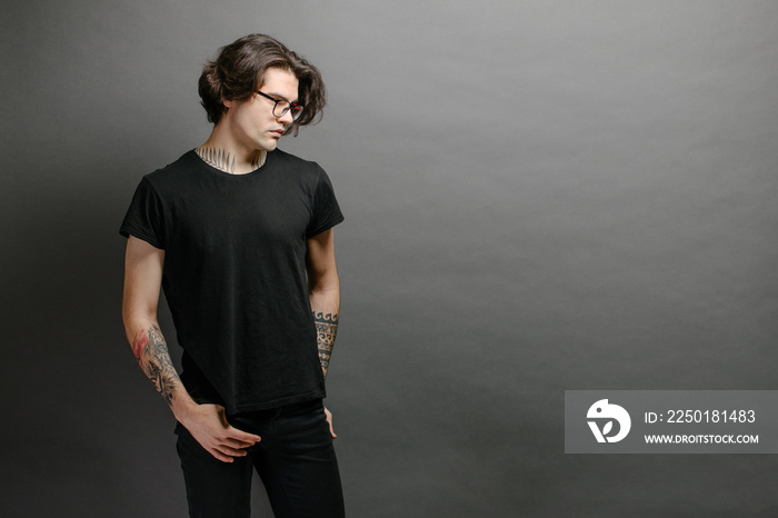 Hipster handsome male model with glasses wearing black blank t-shirt and black jeans with space for 