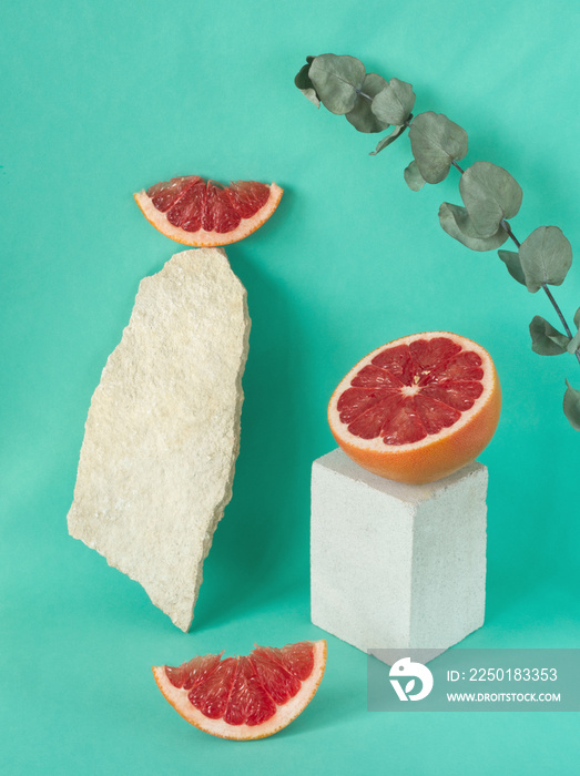 成熟、新鲜的葡萄柚片在薄荷绿背景下的白色石台上的成分。柑橘