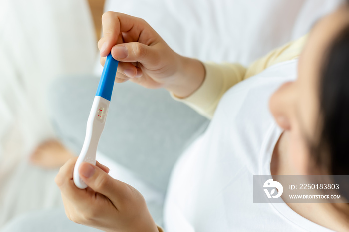 Happy pregnant woman holding pregnancy test, examine positive test, young lady has baby or fetus in 