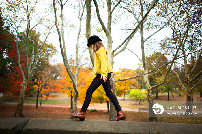 Girl (8-9) walking on wall in park