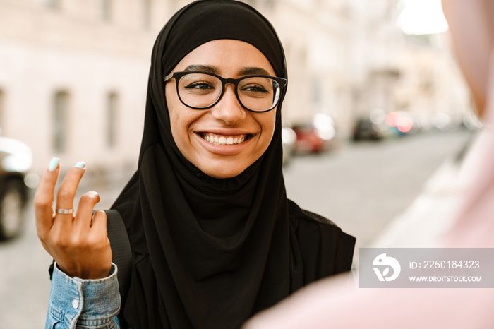 Young muslim women smiling while talking at city street