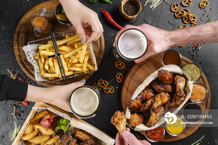 Group of friends drinking beer and eating snacks on wooden background