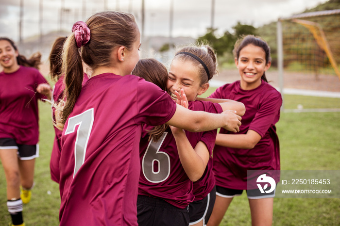 Cheerful girls embracing while celebrating success on soccer field