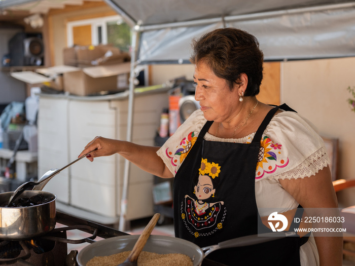 一位土著妇女在准备土著食物时微笑的水平图像