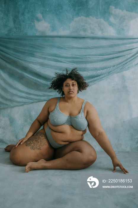 portrait of a plus size afro indigenous person sitting on the floor looking at camera