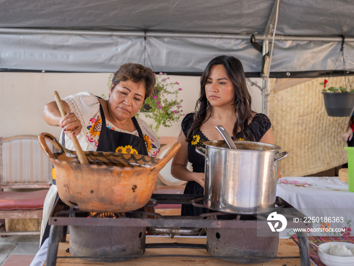 Indigenous elder mixing mole next to her daughter