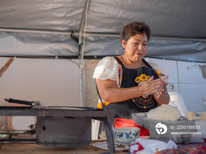 Indigenous woman rolling masa by hand and making tortillas